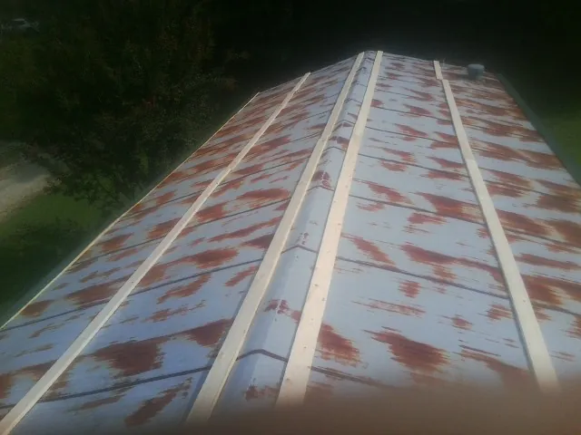 Rusted metal roof panels with new wood purlins before replacement in Kingsbury