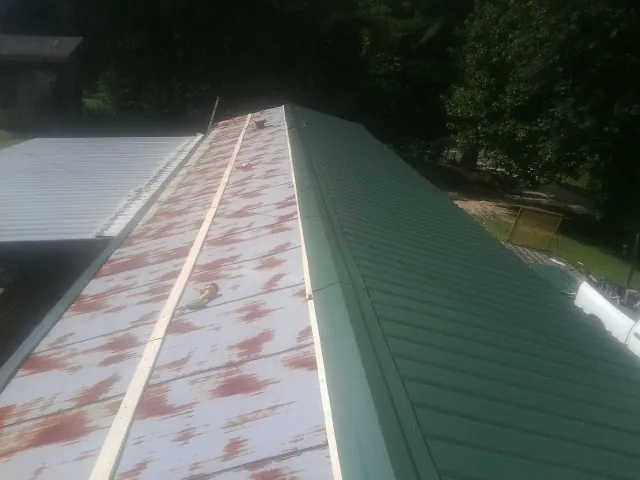 Old rusted panels beside newly installed green metal roofing — Wind Damage Roof Repair by Roofing Brothers in Kingsbury
