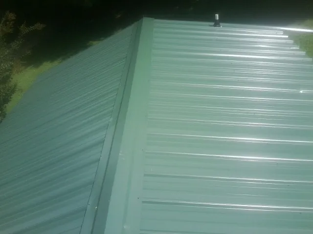 New green metal panels meeting at the ridge of a roof — Flat Roof Repair work by our crew in Kingsbury