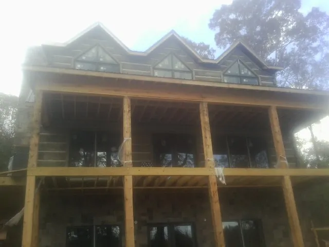 Dormers and porch framing on a large log home under construction — Roof Coating work by our crew in Kingsbury