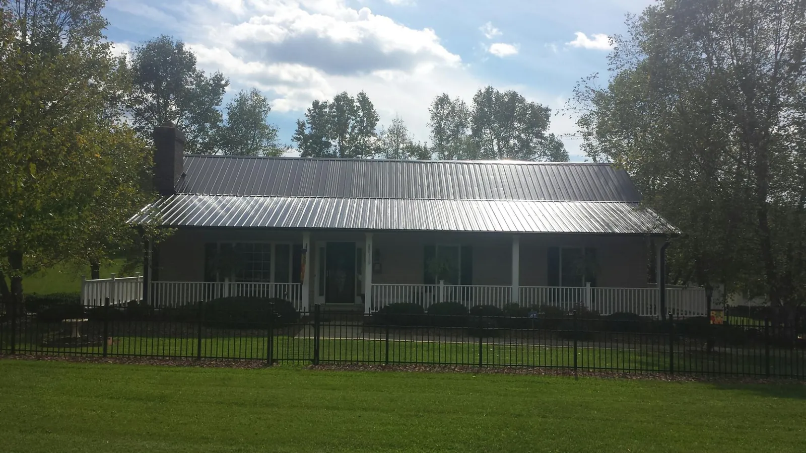 Gray metal roof on a brick ranch with a full width front porch — Gutter Guard Installation work by our crew in Kingsbury